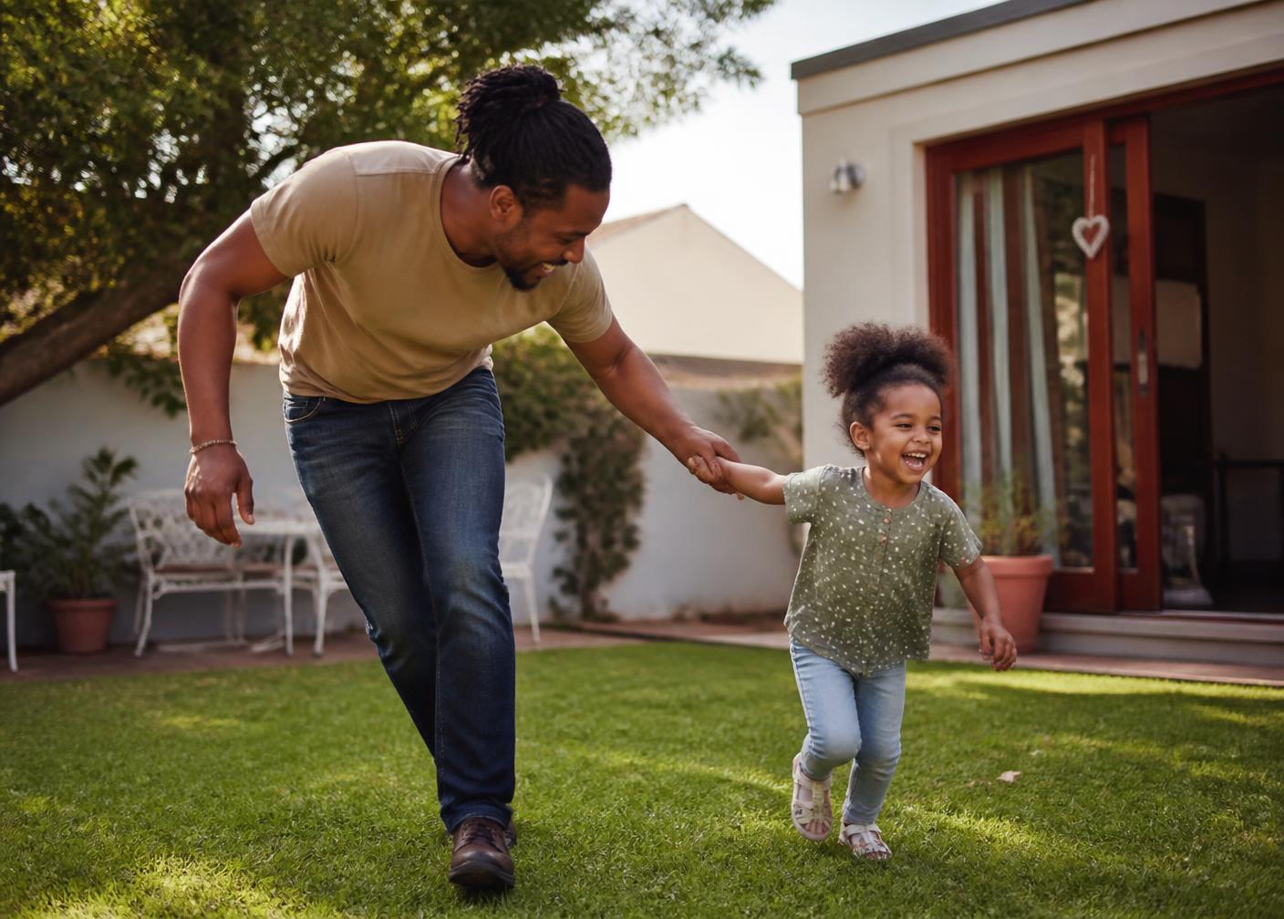 A parent and child playing in a sunlit garden